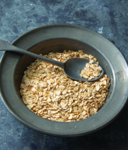bowl of uncooked rolled oats with spoon inside